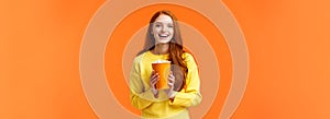 Cheerful cute redhead curly girlfriend holding popcorn chat with boyfriend before movie start at cinema, smiling
