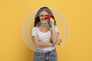 Cheerful cute young indian woman closing eyes with credit card