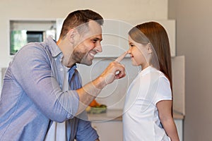 Cheerful Dad Touching Little Daughter& x27;s Nose Posing In Kitchen, Side-View