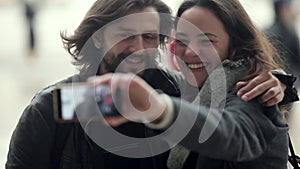 Cheerful dating couple wearing overcoats, standing in city