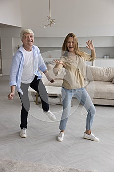 Cheerful daughter and happy energetic old senior dad dancing together