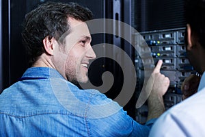 Cheerful delighted man pointing at the server rack