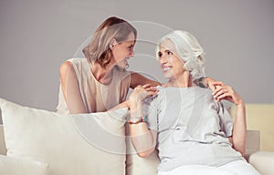 Cheerful delighted mother and her adult daughter resting at home