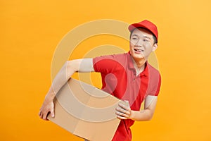 Cheerful delivery man. Happy young courier holding a cardboard box and smiling while standing against white background