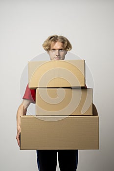Cheerful delivery man. Happy young courier holding a cardboard boxes and smiling while standing against white background
