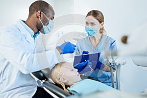 Cheerful dentist dictating his observations to the nurse