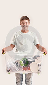 Cheerful disabled boy with Down syndrome smiling at camera while holding a recycling bin full of paper waste, standing