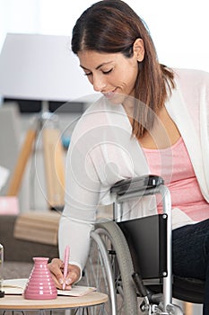 cheerful disabled woman writing in notebook at home photo