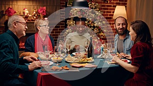 Cheerful diverse family enjoying Christmas dinner at home while eating traditional home cooked food