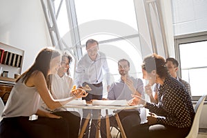 Cheerful diverse team people laughing at joke eating pizza toget