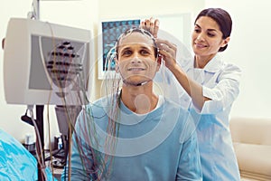 Cheerful doctor adjusting electrodes before electroencephalography analysis photo