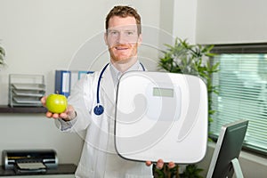 cheerful doctor holding weight scale and apple