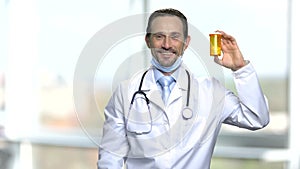 Cheerful doctor showing bottle of pills.