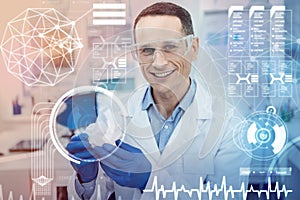 Cheerful doctor smiling and using futuristic technologies in his work