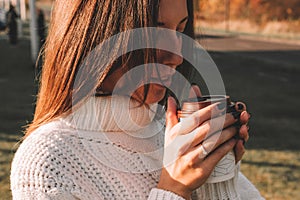 Cheerful drinking coffee. Happy young girl with cup of tea in sunshine light enjoying her morning coffee. Beautiful woman