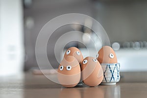 Cheerful easter eggs on the kitchen table, easter egg hunt, egg characters with funny faces, easter concept, kitchen in the backgr