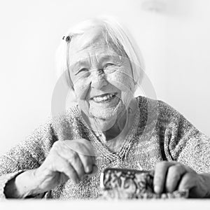 Cheerful elderly 96 years old woman sitting at table at home happy with her pension savings in her wallet after paying