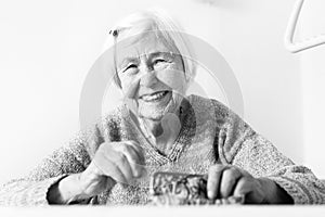 Cheerful elderly 96 years old woman sitting at table at home happy with her pension savings in her wallet after paying
