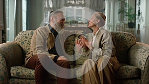 Cheerful elderly couple talking at luxury home. Tender relationship concept.