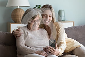 Cheerful elderly grandma and adult granddaughter talking on video call