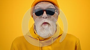 Cheerful elderly man goofing in studio. Mature guy showing tongue indoors.