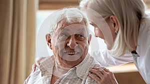 Cheerful elderly man looking at pleasant middle aged nurse.