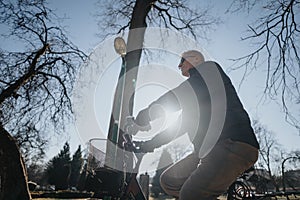 A cheerful elderly man rides a bike in a sunlit park, embodying active lifestyle and healthy aging. Back lit scene with
