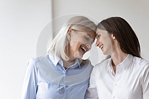 Cheerful elderly mother touch foreheads adult daughter laughing enjoy moment