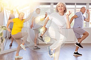 Cheerful elderly woman learning dynamic dances at group choreography lesson