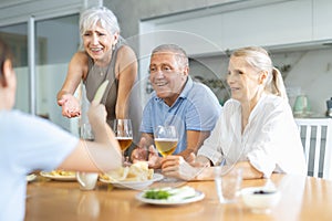 Cheerful elderly women and man gathering around kitchen table