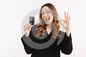 Cheerful elegant woman in coat holding credit card