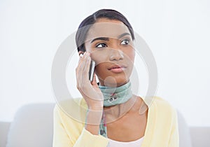 Cheerful elegant woman sitting on sofa having a phone call