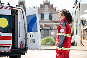 Cheerful emergency doctor posing for the camera beside the ambulance