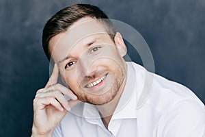 Cheerful employee, joyful expression, vacation starts, white shirt, dark background. Successful businessman