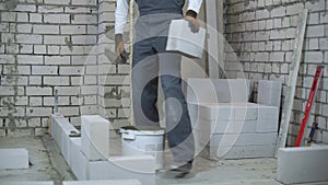 Cheerful and energetic young builder moisturing block with water sprayer