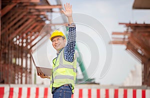 Cheerful engineer man checking project at the building site, Man in hardhat with laptop at the infrastructure construction site