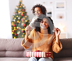 Cheerful ethnic family: happy child and mother congratulate each other at Christmas