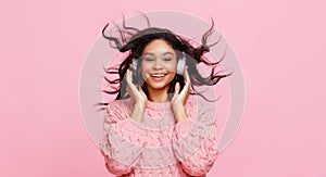 Cheerful ethnic female shaking hair and listening to music
