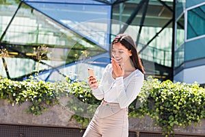 cheerful ethnicity female university student texting on her cell phone in front of a campus