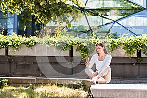 cheerful ethnicity female university student texting on her cell phone in front of a campus