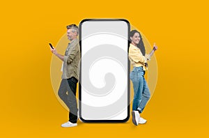 Cheerful European couple leaning on huge smartphone