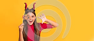 cheerful evil child in imp horns. happy halloween. devil kid with pumpkin party accessory. Halloween kid girl portrait