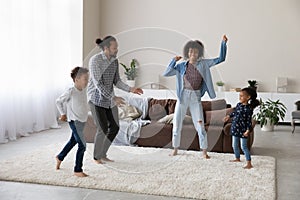 Cheerful excited active African family dancing to music, going wild