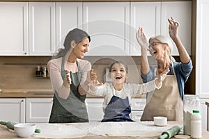 Cheerful excited kid girl, mom and grandma throwing flour powder