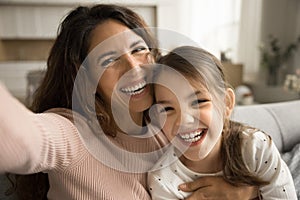 Cheerful excited mom and little kid taking selfie at home