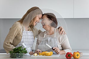 Cheerful excited senior mom and adult daughter enjoying culinary together