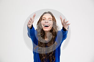 Cheerful excited young woman reaching hands to camera