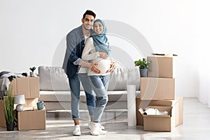 Cheerful expecting couple buying new house, full length shot