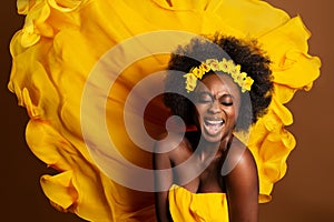 Cheerful Expression Afro American Model over Yellow Silk Flying Fabric Background. Happy Smiling Young Dark Skinned Woman Singing