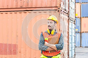 Cheerful factory worker man in hard hat smiling with arms crossed and holding clipboard checklist